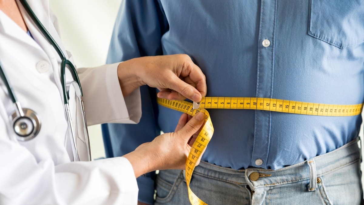 Doctor that measures the waist of obese man