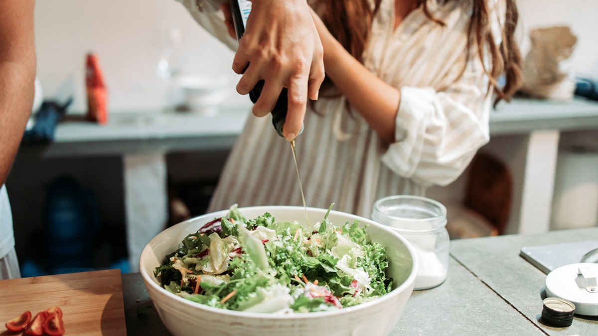 Women dresses salad with oil