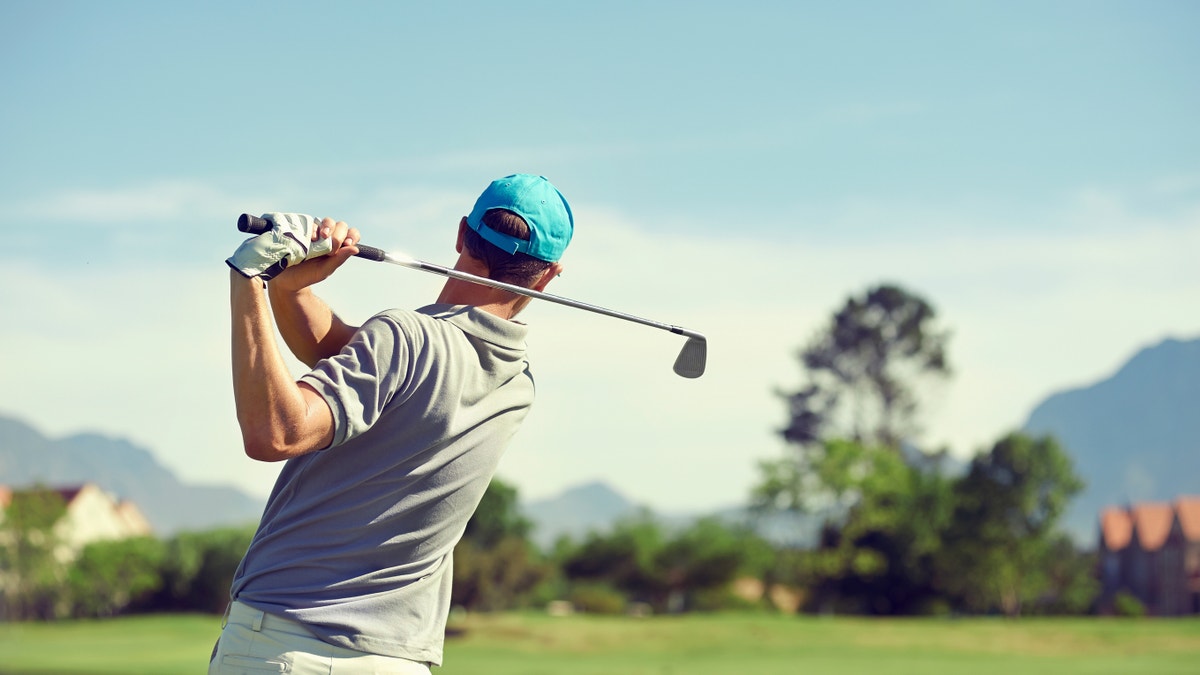 The golfist hit the golf with the club during the summer holidays